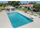 Community pool surrounded by lounge chairs and tables for relaxation at 4885 Tamarack Trl, Venice, FL 34293