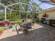 Spacious screened patio with seating, a swing, lush plants, and a grill perfect for outdoor entertaining at 4885 Tamarack Trl, Venice, FL 34293