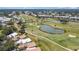 Aerial view featuring a golf course, a tranquil lake, and residential buildings nestled within lush greenery at 542 Clubside Cir # 20, Venice, FL 34293