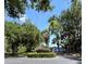 Neighborhood entrance with landscaped roundabout featuring vibrant flowerbeds, mature trees, and well-kept greenery at 542 Clubside Cir # 20, Venice, FL 34293
