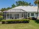 Back exterior view featuring a screened lanai and well-maintained lawn at 553 Fallbrook Dr, Venice, FL 34292