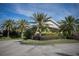 Lushly landscaped community entrance with swaying palms and vibrant flowering bushes at 553 Fallbrook Dr, Venice, FL 34292