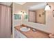 Bright bathroom features a single sink vanity, a large mirror, and a shower with pink curtain at 6451 Keena Ct, North Port, FL 34287
