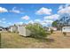 Property exterior featuring mature tree and well-manicured lawn under a bright blue, cloudy sky at 6451 Keena Ct, North Port, FL 34287