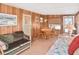 Comfortable living room with wood paneling, sofa, dining table, and natural light enhancing its charm at 6451 Keena Ct, North Port, FL 34287