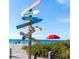 Beach scene with directional signpost, blue sky, and red umbrella under clear, sunny skies at 649 Tamiami S Trl # 106, Venice, FL 34285