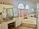 Large primary bathroom showcasing a soaking tub under decorative windows and separate shower at 6507 Drewry'S Blf, Bradenton, FL 34203