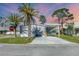 View of the side of the home, showcasing the covered parking and mature palm trees at 6803 Amoko Ct, North Port, FL 34287
