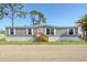 Charming gray single-story home with white trim, manicured lawn, and a wooden porch at 6803 Amoko Ct, North Port, FL 34287