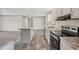 Open kitchen and floor plan features an island, stainless appliances, and modern wood-look flooring at 6803 Amoko Ct, North Port, FL 34287