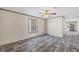 Bright living room featuring gray wood-look floors, a ceiling fan, and a sunlit window at 6803 Amoko Ct, North Port, FL 34287
