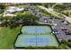 This aerial view showcases tennis courts, a parking lot, and lush landscaping at 872 Macaw Cir, Venice, FL 34285