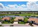 Expansive aerial view of a luxurious home with a tile roof, lush landscaping, and a serene lake and golf course backdrop at 872 Macaw Cir, Venice, FL 34285