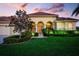 Inviting home exterior with arched entryway, lush landscaping, and a well-maintained lawn, showcasing curb appeal at 872 Macaw Cir, Venice, FL 34285