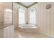 Luxurious primary bathroom with a glass enclosed shower, and a soaking tub nestled between two arched windows at 872 Macaw Cir, Venice, FL 34285