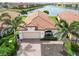 Aerial view of this charming home, landscaped yard, tile roof, and serene lake views at 10093 Cozy Grove Dr, Venice, FL 34293