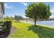 Serene backyard view featuring a tranquil lake, lush green grass, and mature trees at 10093 Cozy Grove Dr, Venice, FL 34293