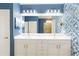 Elegant bathroom with double vanity, decorative wallpaper, and large mirror with modern lighting at 10093 Cozy Grove Dr, Venice, FL 34293