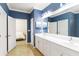 Bright bathroom features double sinks, white cabinetry, and a doorway leading into the primary bedroom at 10093 Cozy Grove Dr, Venice, FL 34293