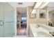 The bathroom features a dual sink vanity with frosted glass shower door and a glimpse into the bedroom at 1018 Wexford Blvd # 1018, Venice, FL 34293
