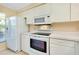 Well-lit white kitchen with standard appliances including a refrigerator, oven, and microwave at 1018 Wexford Blvd # 1018, Venice, FL 34293