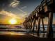 Tranquil sunset view under the pier on a sandy beach, reflecting the golden sunlight on the water at 1025 Capri Isles Blvd # 18, Venice, FL 34292