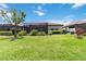 Large grassy backyard featuring a screened lanai, lush landscaping, and mature trees at 10618 Corkwood Ct, Venice, FL 34293