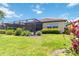 Home with a screened-in lanai, a grassy yard, and lush landscaping at 10618 Corkwood Ct, Venice, FL 34293