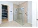 Bathroom featuring frameless glass shower with tile surround and built in shelving next to open closet at 10618 Corkwood Ct, Venice, FL 34293