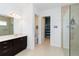 Contemporary bathroom featuring dual vanity, tiled walk-in shower, and convenient linen closet at 10618 Corkwood Ct, Venice, FL 34293