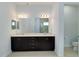 Bright bathroom featuring double sinks, granite countertops, and a large mirror reflecting the walk-in shower and toilet at 10618 Corkwood Ct, Venice, FL 34293