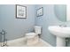 Powder room featuring a sleek pedestal sink and toilet in a light blue painted room at 10618 Corkwood Ct, Venice, FL 34293