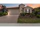 Charming home with a two-car garage, brick driveway, manicured landscaping, and beautiful sunset at 10618 Corkwood Ct, Venice, FL 34293