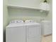 Functional laundry room with white appliances, a sink, cabinet, and shelving at 10618 Corkwood Ct, Venice, FL 34293
