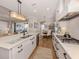 Open kitchen with white cabinets, quartz countertops, stainless appliances, an island with bar seating, and hardwood floors at 10973 Trevino St, Englewood, FL 34223