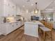 Modern kitchen with white cabinets, stainless steel appliances, a large island with seating, and hardwood floors at 10973 Trevino St, Englewood, FL 34223