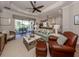 Bright living room with hardwood floors, a ceiling fan, and a view of the outdoor patio and pool area at 10973 Trevino St, Englewood, FL 34223