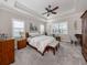 Serene primary bedroom with a tray ceiling, large windows, neutral tones, and a seating area, creating a relaxing retreat at 10973 Trevino St, Englewood, FL 34223