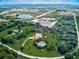 Expansive aerial view of a beautiful estate featuring lush landscaping, a private pond, pool, and neighboring commercial area at 1104 Twin Laurel Blvd, Nokomis, FL 34275