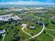 Drone's-eye view of the home on a sprawling green space that features pond, generous landscaping, and lengthy winding driveway at 1104 Twin Laurel Blvd, Nokomis, FL 34275