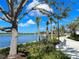 Scenic view of community lake and walking path lined with palm trees and lush landscaping under a bright blue sky at 12478 Sagewood Dr, Venice, FL 34293