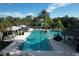 A serene community pool featuring covered seating areas, lounge chairs, and tropical landscaping at 12478 Sagewood Dr, Venice, FL 34293