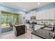 Well-equipped kitchen with granite countertops, white cabinetry, and a movable island for extra prep space at 12478 Sagewood Dr, Venice, FL 34293
