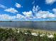 Picturesque lake view featuring clear water, a distant shoreline, and a bright, cloudy sky at 12478 Sagewood Dr, Venice, FL 34293