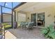Screened patio with a ceiling fan, table, grill, sliding glass doors, and brick pavers at 12478 Sagewood Dr, Venice, FL 34293