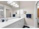 Bathroom features a dual sink vanity with mirror, light fixtures, white cabinets, blue accents and wall storage at 129 Preserve Pl # D, Nokomis, FL 34275