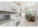 Bright kitchen featuring white cabinets, granite countertops, and a cozy dining area with shuttered windows at 129 Preserve Pl # D, Nokomis, FL 34275