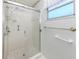 Tiled shower with sliding glass doors and window providing natural light at 1320 Whispering Ln, Venice, FL 34285