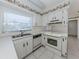 White kitchen featuring laminate countertops, white appliances, and a sunny window at 1320 Whispering Ln, Venice, FL 34285