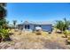 Large backyard with playset, swing, tropical plants, and mature trees under a clear blue sky at 13579 Romford Ave, Port Charlotte, FL 33981